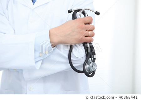 Close Up of Unknown male doctor standing straight while holding stethoscope. Medicine and health Close Up of Unknown male doctor standing straight while holding stethoscope. Medicine and health 40868441