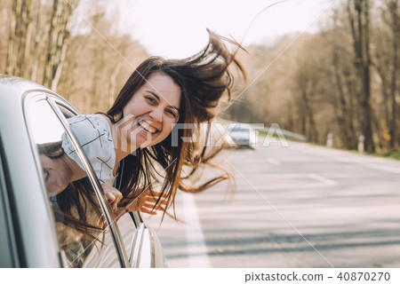 young pretty woman stick out of car window. wind blowing woman hair young pretty woman stick out of car window. wind blowing woman hair 40870270