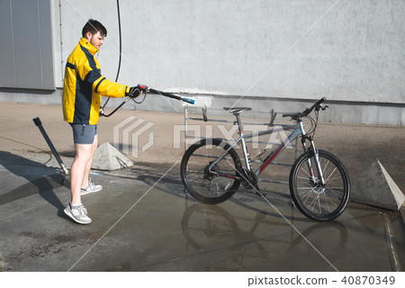 young man washing bicycle at carwash. lifestyle young man washing bicycle at carwash. lifestyle 40870349