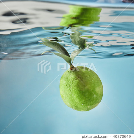 Fresh lime dropped into water with splash isolated on blue Fresh lime dropped into water with splash isolated on blue 40870649