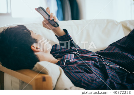 看起來一個年輕日本的人說謊和觀看智能手機 40872238