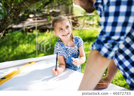 Father with a small daughter outside, planning wooden birdhouse. Father with a small daughter outside, planning wooden birdhouse. 40872783