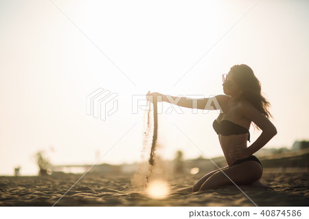 Sexy girl sunbathing on a beach and plays with sand Sexy girl sunbathing on a beach and plays with sand 40874586