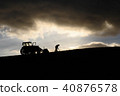 Silhouette of farmer working next to his tractor 40876578