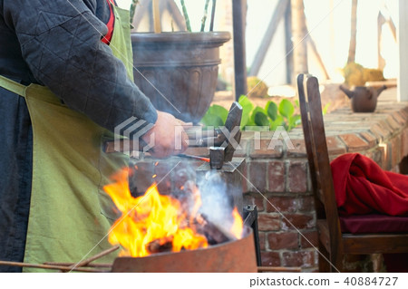 Close-up of blacksmith manually forging the molten metal on the anvil in smithy workshop. Close-up of blacksmith manually forging the molten metal on the anvil in smithy workshop. 40884727