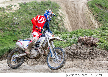 Professional Motocross Motorcycle Rider Drives Over the Road Track. Professional Motocross Motorcycle Rider Drives Over the Road Track. 40887989