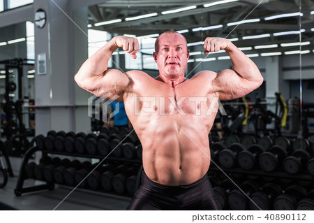 Bodybuilder man with perfect biceps, triceps and chest in the gym Bodybuilder man with perfect biceps, triceps and chest in the gym 40890112