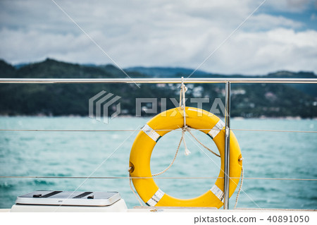 Close-up Yellow life ring hanging on boat with ocean background. Close-up Yellow life ring hanging on boat with ocean background. 40891050