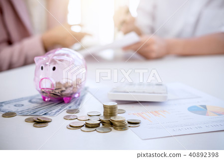 Two couples putting coins into piggy bank, writing to report and Two couples putting coins into piggy bank, writing to report and 40892398