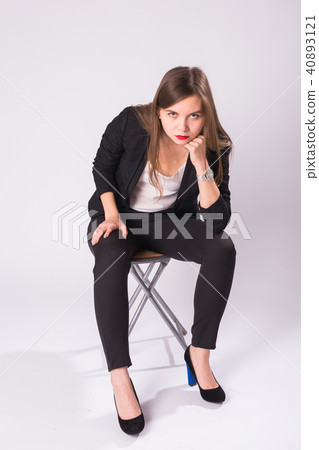 beautiful young business woman in black suit sits on a chair on white background beautiful young business woman in black suit sits on a chair on white background 40893121