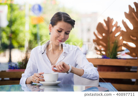 Modern young woman sitting in a cafe and waiting for someone looking to her watches Modern young woman sitting in a cafe and waiting for someone looking to her watches 40897711