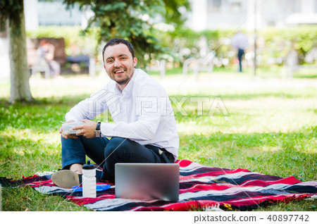 Young and attractive man relaxes in the park at lunch time 40897742