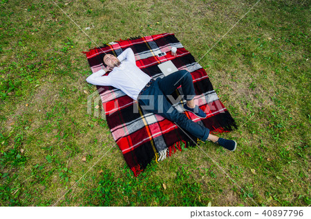Happy young man with laptop relaxing on the grass, view from the top Happy young man with laptop relaxing on the grass, view from the top 40897796