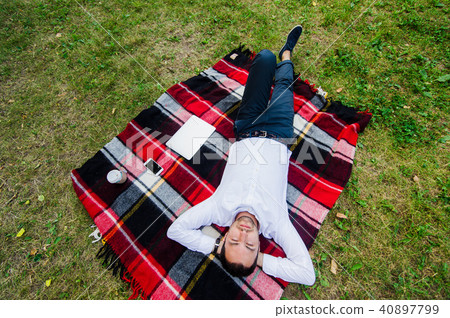 Happy young man with laptop relaxing on the grass, view from the top Happy young man with laptop relaxing on the grass, view from the top 40897799