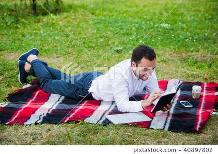 Young business man reading book outside in a park Young business man reading book outside in a park 40897802