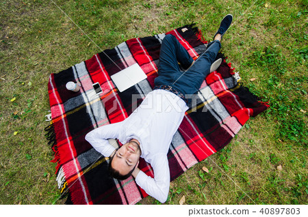 Happy young man with laptop relaxing on the grass, view from the top Happy young man with laptop relaxing on the grass, view from the top 40897803