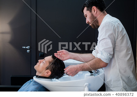 Hairstylist Hairdresser Washing Customer Hair - Young Man Relaxing In Hairdressing Beauty Salon Hairstylist Hairdresser Washing Customer Hair - Young Man Relaxing In Hairdressing Beauty Salon 40898372