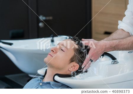 Close-up of a young man having his hair washed in hairdressing salon Close-up of a young man having his hair washed in hairdressing salon 40898373