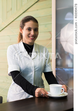 Female nurse at desk making coffee working in a modern office Female nurse at desk making coffee working in a modern office 40899478