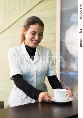 Female nurse at desk making coffee working in a modern office Female nurse at desk making coffee working in a modern office 40899479