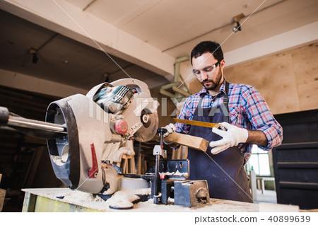 Carpenter working on an electric buzz saw cutting some boards, he is wearing safety glasses 40899639