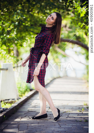 Beautiful, pretty woman in casual checkered dress walking at park outdoors. Street fashion style. Beautiful, pretty woman in casual checkered dress walking at park outdoors. Street fashion style. 40900961