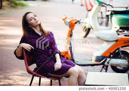 young attractive girl with beautiful smile wearing violet checkered dress and vintage old scooter young attractive girl with beautiful smile wearing violet checkered dress and vintage old scooter 40901208