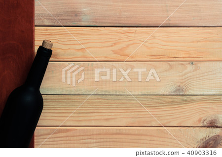 Black bottle of red wine on a wooden table.  40903316