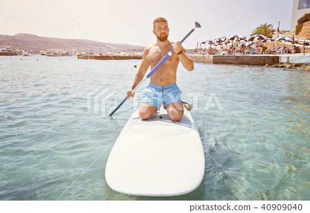 Bearded man beginner surfer kneel on paddle board 40909040