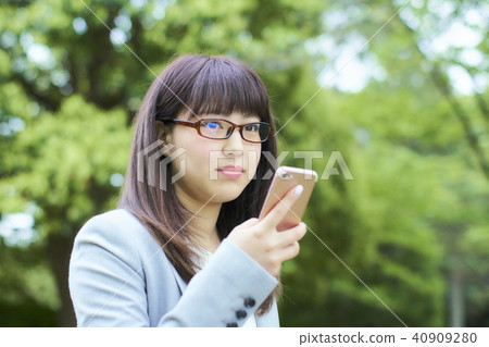 操作智能手機的一個少婦在公園 40909280