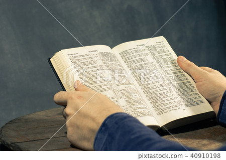 Young man sitting at a table reading Holy Bible 40910198