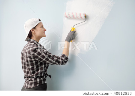 Girl painter, designer and worker paints a roller and brush the wall. Smiling, working with pleasure 40912833