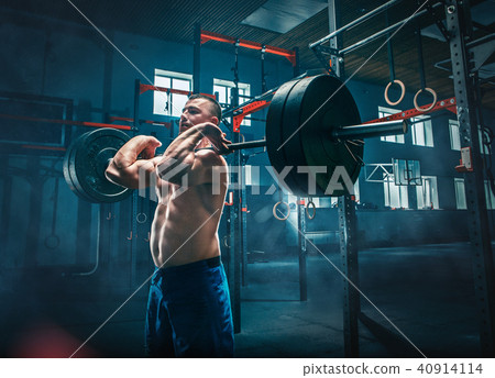 Fit young man lifting barbells working out in a gym Fit young man lifting barbells working out in a gym 40914114