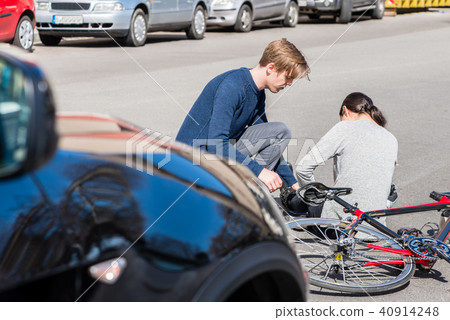 Helpful young man giving first aid to an injured woman after bicke accident Helpful young man giving first aid to an injured woman after bicke accident 40914248