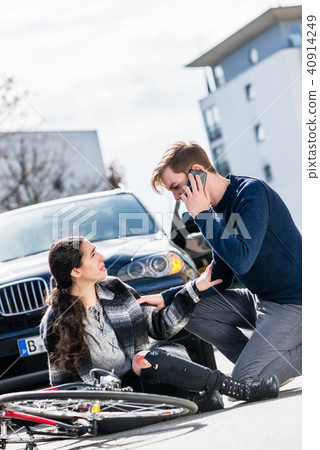 Young man calling the emergency services after hitting a bicyclist Young man calling the emergency services after hitting a bicyclist 40914249
