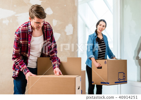 Young man opening a box while moving in with his girlfriend Young man opening a box while moving in with his girlfriend 40914251