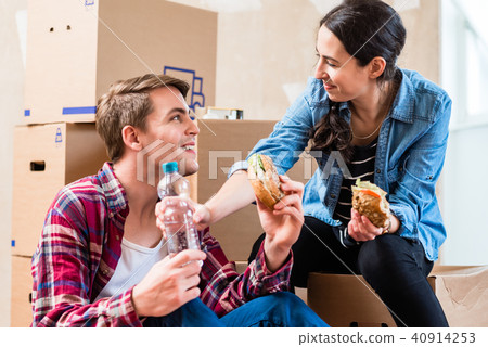Young couple looking tired while eating a sandwich during renovation Young couple looking tired while eating a sandwich during renovation 40914253