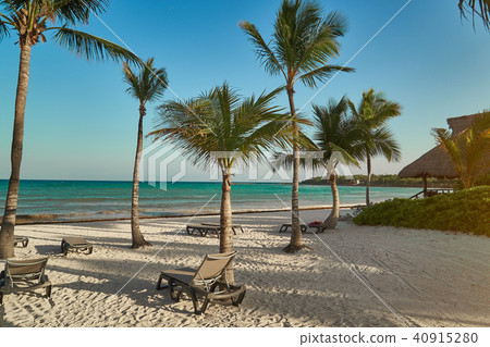 View at luxury resort hotel beach of tropical coast. Leaves of coconut palms fluttering in wind View at luxury resort hotel beach of tropical coast. Leaves of coconut palms fluttering in wind 40915280