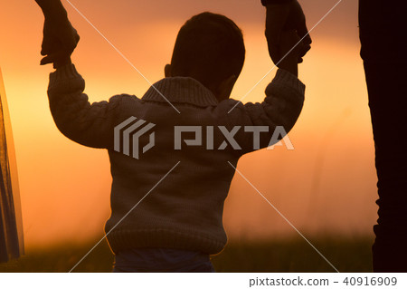Dad and mom raise the baby in the air, the family has fun - silhouette Dad and mom raise the baby in the air, the family has fun - silhouette 40916909