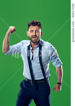 The young emotional angry man screaming on green studio background The young emotional angry man screaming on green studio background 40917099