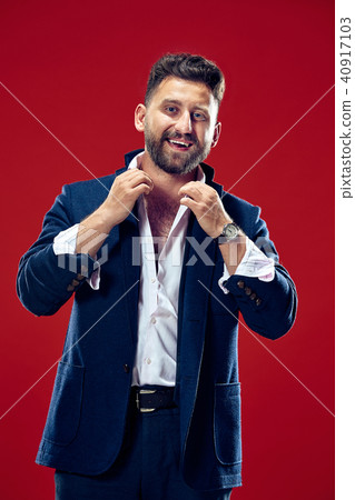 The happy business man standing and smiling against red background. 40917103