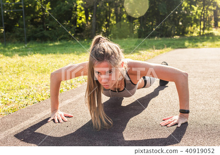 Fitness woman doing push-ups during outdoor cross training workout. Beautiful young and fit fitness 40919052