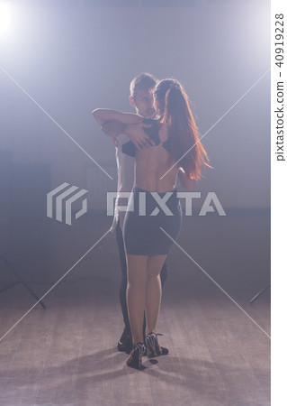 Skillful dancers performing in the dark room under the concert light and smoke. Sensual couple 40919228