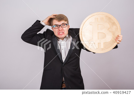 Portrait of a angry businessman holds big golden bitcoin in his arms. Man in panic of cryptocurrency 40919427