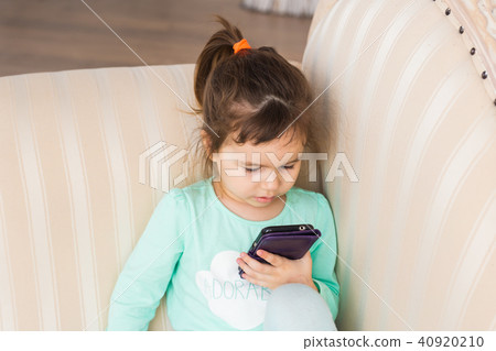 Little girl with smartphone in room Little girl with smartphone in room 40920210
