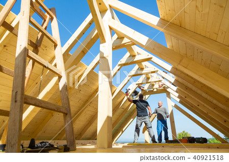 Builders at work with wooden roof construction. 40921518