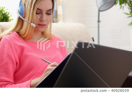 young beautiful blond woman sit on the sofa in livingroom hold binder in arms work with laptop young beautiful blond woman sit on the sofa in livingroom hold binder in arms work with laptop 40926039