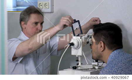 Senior optometrist doing sight testing for patient 40929067