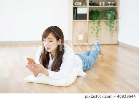 A lady who lies down and touches a smartphone A lady who lies down and touches a smartphone 40929644