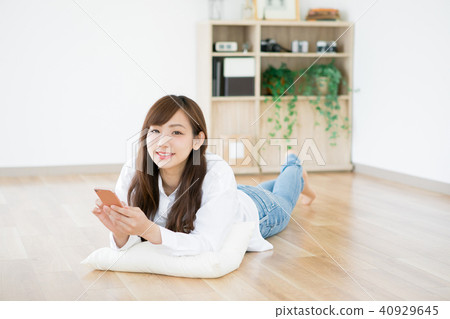 A lady who lies down and touches a smartphone A lady who lies down and touches a smartphone 40929645